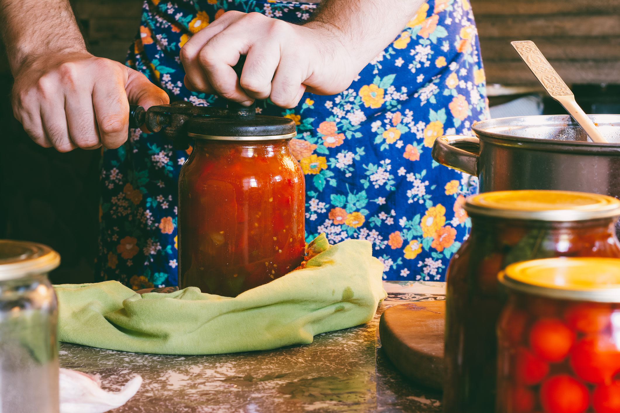A lady sealing a lid on a jar of fruit.